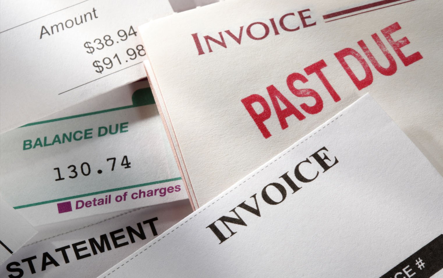 Stack of papers with "invoice," "past due" and "balance due"due prominently displayed on each